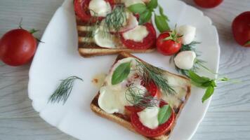 gebraten heiß Toast mit Mozzarella und Tomaten im ein Teller auf ein hölzern Tabelle video