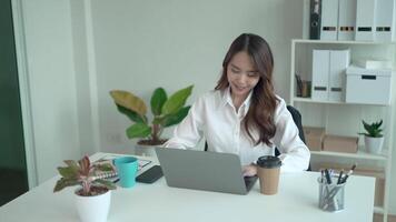 después trabajando difícil para un mientras, joven asiático mujer relaja después trabajo sonriente felizmente divertido después trabajo video