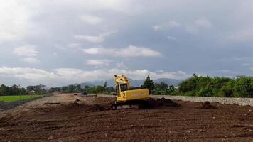 väst lombok regentskap, indonesien - februari 4, 2024. utomhus, en traktor är på arbete utjämning de jord för en hus webbplats, med en blå himmel i de bakgrund. video