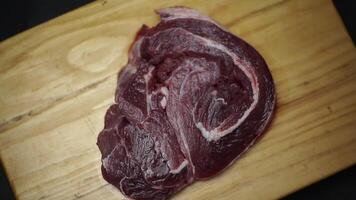 Raw steak in wooden plate on black background. video