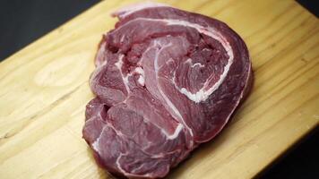 Raw steak in wooden plate on black background. video