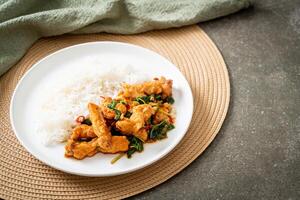 stir-fried fried fish with basil and chili in thai style topped on rice photo