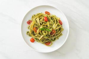 fettuccine spaghetti pasta with pesto sauce and tomatoes photo