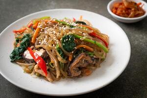 japchae or stir-fried Korean vermicelli noodles with vegetables and pork topped with white sesame photo