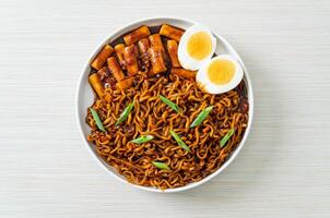 jjajang rabokki - fideos instantáneos coreanos o ramyeon con pastel de arroz coreano o tteokbokki y huevo en salsa de frijoles negros foto