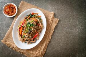 japchae or stir-fried Korean vermicelli noodles with vegetables and pork topped with white sesame photo