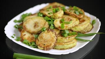 fried zucchini in circles with fresh herbs in a plate on a black background video