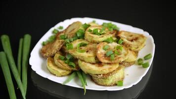 fried zucchini in circles with fresh herbs in a plate on a black background video