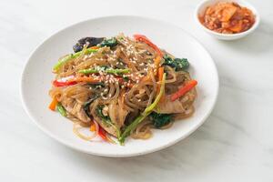 japchae or stir-fried Korean vermicelli noodles with vegetables and pork topped with white sesame photo