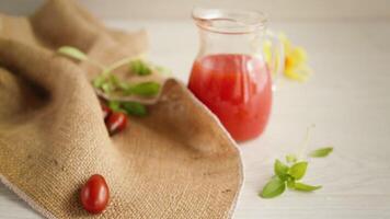 hausgemacht frisch gedrückt Tomate Saft mit Fruchtfleisch im ein Glas Karaffe, auf ein hölzern Tisch. video