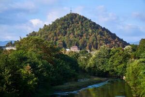 paisaje con un colina, un río y un poder transmisión torre a el parte superior foto