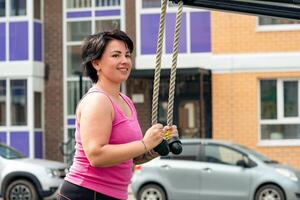 joven mujer ejercicio en palanca máquina al aire libre foto