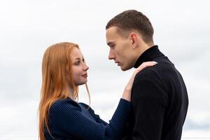 young couple stands hugging on the background of cloudy sky photo