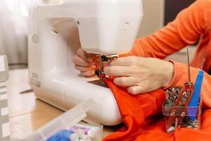 manos de un costurera ajuste un aguja en un de coser máquina foto