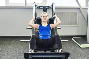 young woman performs squats with exercise machine photo