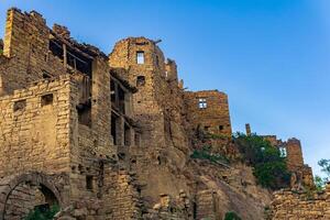 ruined old high stone houses in the abandoned village of Gamsutl, Dagestan photo