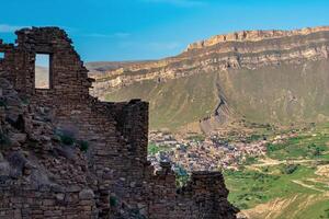 paredes de abandonado casas en un montaña acantilado en el fantasma pueblo de gamsutl en daguestán, en el opuesto lado de el Valle el poblado pueblo de chokh es visible foto