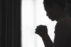 Silhouette of a person praying to god and holy things, religious concept, faith and belief, religious. photo