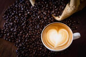 Cup of coffee latte with heart shape and coffee beans on old wooden background, with copy space. photo