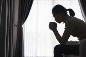 Silhouette of a person suffering from depression in the house, Depressed woman sitting alone on the Sofa feel stress, sad and worried in the dark room. person are stressed. photo