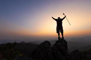 silueta de un trepador a el parte superior de el rocoso montaña a atardecer, hombre en parte superior de montaña. conceptual diseño. solo a el cumbre trepador exitoso escaladores deporte y activo vida. foto