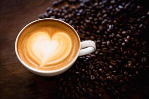Cup of coffee latte with heart shape and coffee beans on old wooden background, with copy space. photo