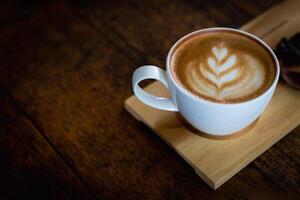 taza de café latté con corazón forma y café frijoles en antiguo de madera fondo, con Copiar espacio. foto