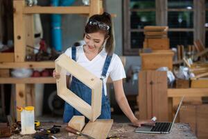 joven mujer es formación a ser un carpintero en taller. carpintero trabajando con equipo en de madera mesa. mujer trabajos en un carpintería tienda. foto