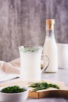 Ayran homemade yogurt drink with dill in a glass on the table vertical view photo