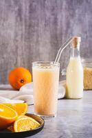 Vegetarian smoothie made from rice milk and orange in a glass on the table vertical view photo