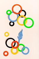 Olympics, Paris, France, summer, 2024. Multi-colored rings and flame on a light vertical view photo