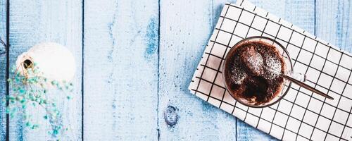 Homemade sweet cake in a mug made in the microwave on the table top view web banner photo