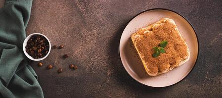 Tiramisu cake made of cookies, delicate cream and coffee on a plate top view web banner photo