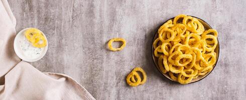 Homemade fried onion rings on a plate and sauce on the table top view web banner photo