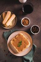 Tiramisu cake made of cookies, delicate cream and coffee on a plate top and vertical view photo