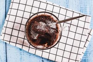 Close up of chocolate cupcake with powdered sugar in a mug on the table top view photo