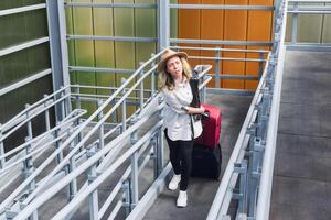 woman tourist with two suitcases moves along a zigzag ramp in a covered overpass photo