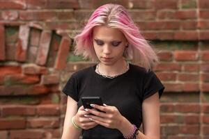 teen girl writes or reads a message using the phone against the background of an old wall photo