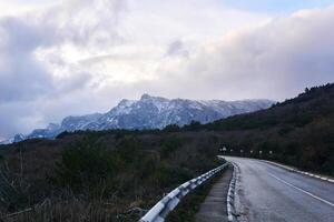 highway in the winter Crimean mountains among the forest and a mountain peak on the horizon photo