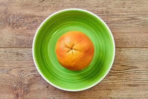 rosado amarillo pomelo en un verde plato en un caña Manteles foto