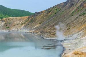 hot mineralized lake with thermal spring and smoking fumaroles in the caldera of the Golovnin volcano on the island of Kunashir photo