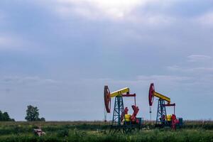 bombas operando a un petróleo bien en campo debajo nublado cielo foto