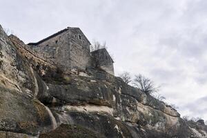 view of the Karaite kenassas on the edge of a cliff in the ancient cave city of Chufut-Kale, Crimea photo