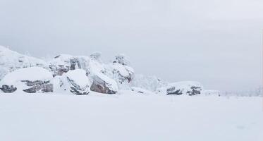 nevadas granito rocas en el medio de blanco silencio debajo un melancólico cielo foto