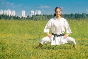 adolescente niña practicando kárate kata al aire libre en kiba-dachi postura foto