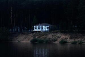 abandoned dilapidated house on a dark wooded bank almost collapsed into the river photo