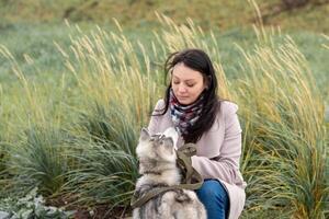 young woman with her dog against the autumn grass in the cold wind photo