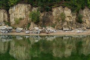 wooded river bank with marble cliffs, water erosion of coastal rocks photo