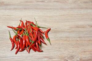 bunch of red hot pepper pods on a wooden surface photo