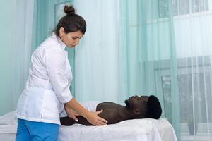 woman masseur doing massage of shoulder area of hand to black man photo